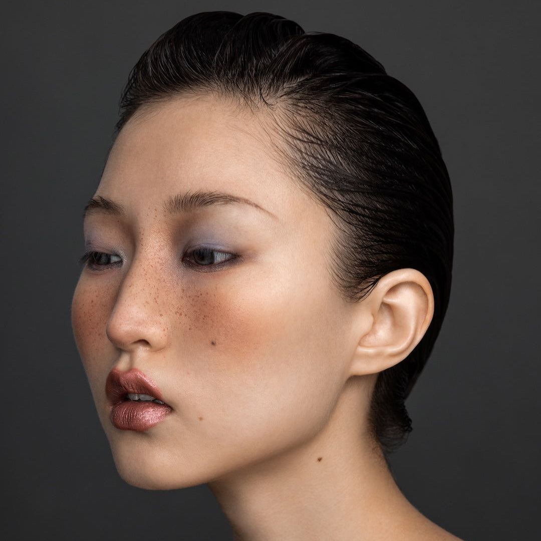 Yann Beyrie editorial slick-back hairstyle with natural freckles and metallic lipstick