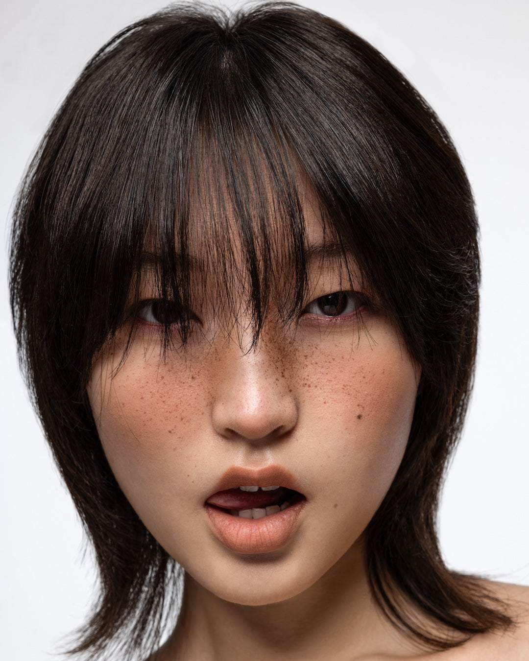 Asian female model with dark layered wolf cut and textured fringe showcasing modern haircut trends