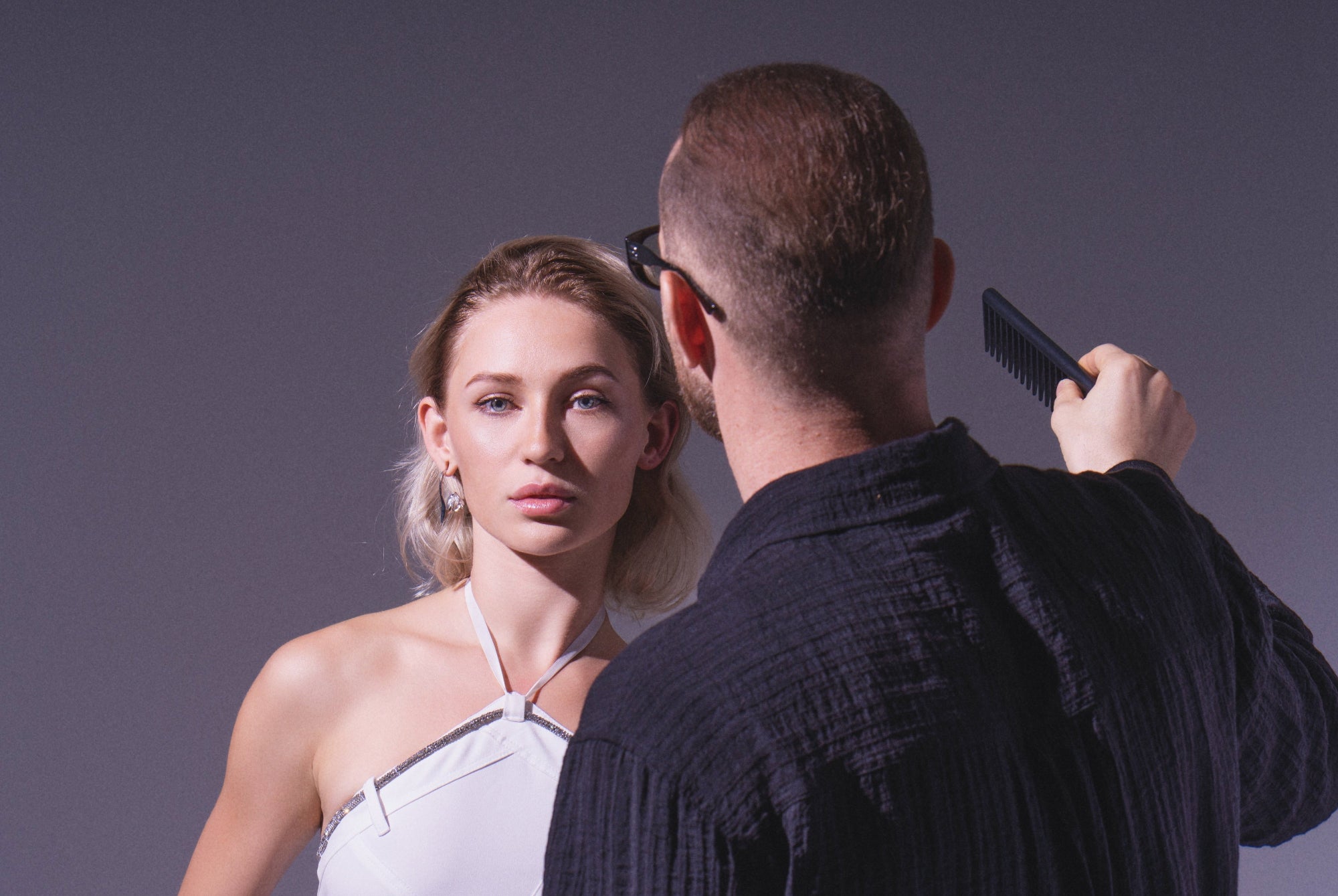 Yann Beyrie styling a blonde model's hair during a professional studio photoshoot