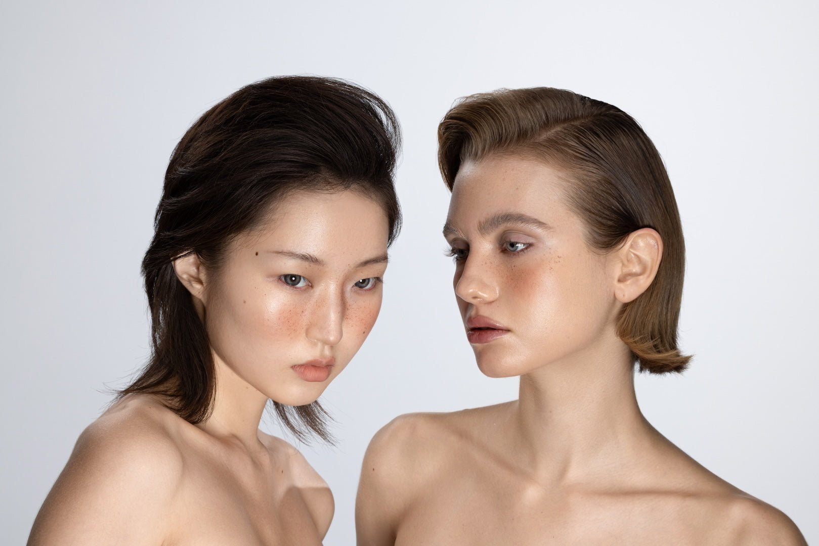 Editorial studio portrait of two female models showcasing voluminous dark layered hair and sleek slicked-back style at Yann Beyrie Paris
